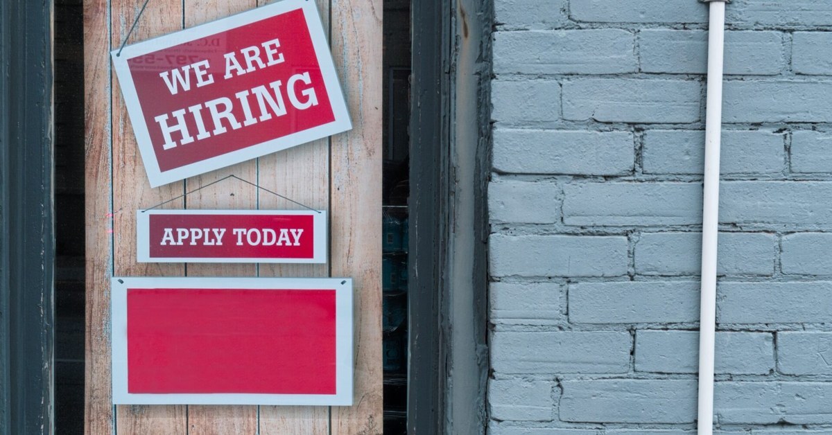 Schild „We are hiring“ im Fenster eines Betriebs mit Personalmangel